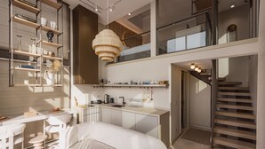 En moderne, åben stue med et køkken, spiseområde og en trappe, der fører op til en etage.