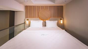 Quarto de hotel moderno com uma cama grande, duas luminárias de cabeceira e uma cabeceira de madeira.