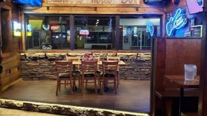 A restaurant with a wooden facade, a stone wall, and a neon sign. - Serenity Lakeside Cottage (Edinboro)