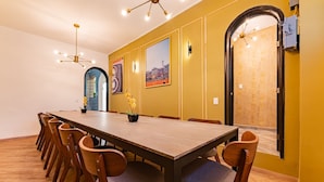 Un comedor con una larga mesa de madera y sillas a juego, una araña y obras de arte enmarcadas en las paredes.