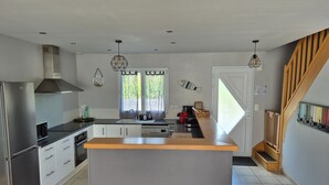 A modern kitchen with a central island, stainless steel appliances, and a wooden staircase.