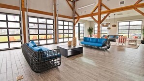 A spacious room with large windows, a wooden ceiling, and a blue sofa.