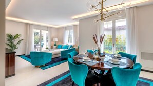 Uma sala de jantar moderna com uma mesa redonda, cadeiras verde-água e um candelabro.