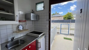 Uma cozinha compacta com pia, micro-ondas e uma pequena janela.