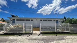 Um edifício com fachada branca, várias portas e um portão de entrada.