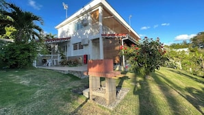 Ein zweistöckiges Haus mit Veranda, kleinem Garten und einem roten Strauch.