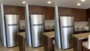 A kitchen with stainless steel appliances, wooden cabinets, and a granite countertop. - Condos PDS (Mazatlán)