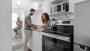 A modern kitchen with white cabinets, a black stove, and a microwave.