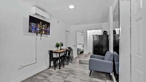 A modern interior with a dining area, a seating area, and a large black refrigerator.