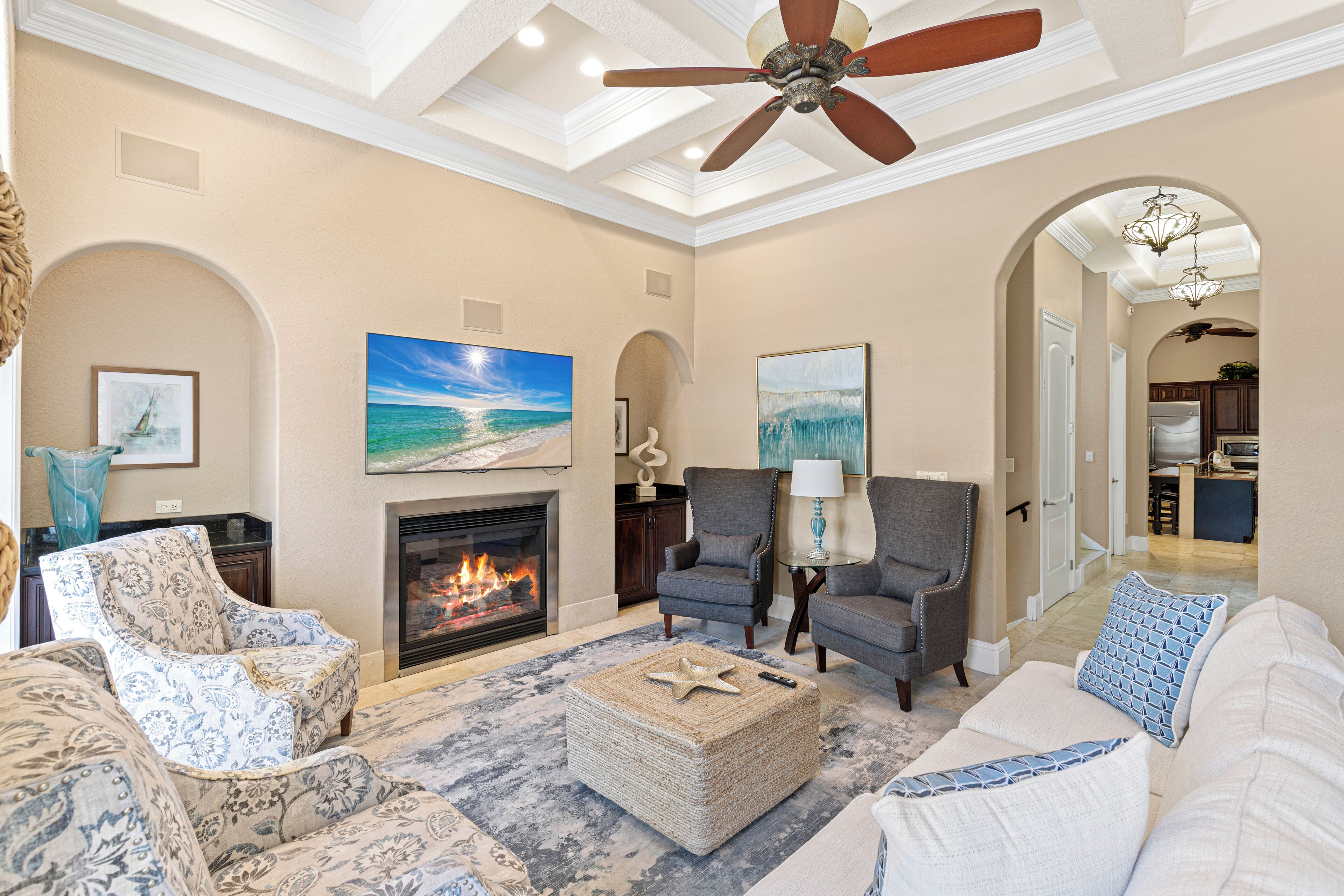 A spacious living room with a fireplace, comfortable seating, and a ceiling fan.