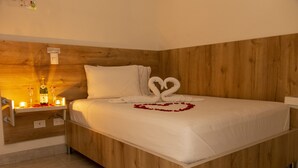Ein ordentlich bezogenes Bett mit weißen Leinen und einer herzenförmigen Anordnung aus Rosenblättern auf der Tagesdecke.