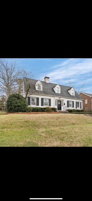 A two-story house with a front porch, a chimney, and a well-maintained lawn.
