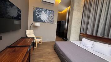 Une chambre d’hôtel avec un lit, un bureau, une chaise, une télévision et un tableau au mur.