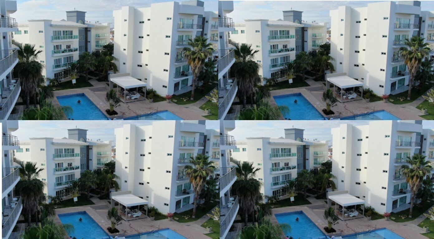 Un hotel moderno con varios balcones, una piscina y abundante vegetación.