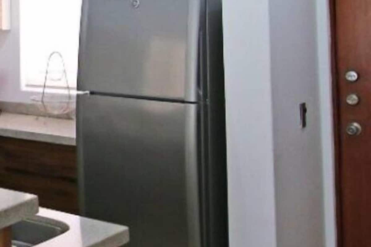 Una cocina con un refrigerador de acero inoxidable, un armario de madera y piso de baldosas.