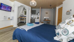 A hotel room with a bed, a TV, a kitchenette, and a bathroom. - Santorini bed and breakfast with terrace and swimming pool (Montreuil)