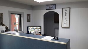 A reception desk with a computer monitor, a 'WELCOME' sign, and a 'LOVE' sign on the wall. - OYO Hotel Pensacola I-10 & Hwy 29 (Pensacola)