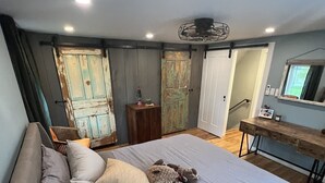Un dormitorio con una cama grande, un aparador de madera, un espejo y un ventilador de techo.