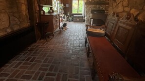Un interior rústico con pared de piedra, banco de madera y lámpara colgante.
