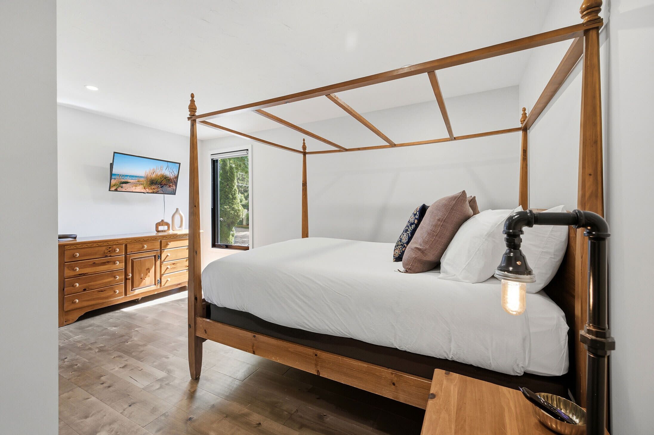 Una cama con dosel de madera, ropa de cama blanca y una lámpara de noche.