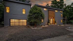 A modern two-story house with a garage, large windows, and a well-maintained garden.