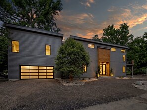 Une maison moderne à deux étages, dotée d’un garage, de grandes fenêtres et d’un jardin bien entretenu.