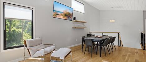 A modern interior with a dining area, a sofa, and a TV mounted on the wall.
