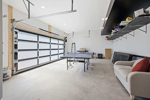 Uma garagem com mesa de pingue-pongue, sofá e estante.