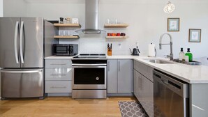 A modern kitchen with stainless steel appliances, a microwave, oven, and a dishwasher.