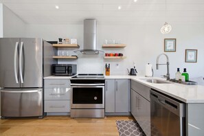 Une cuisine moderne équipée d’appareils électroménagers en acier inoxydable, d’un four à micro-ondes, d’un four traditionnel et d’un lave-vaisselle.