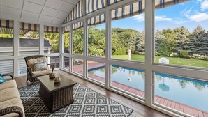 Un patio cubierto con vistas a una piscina, muebles de mimbre y un tapete estampado.