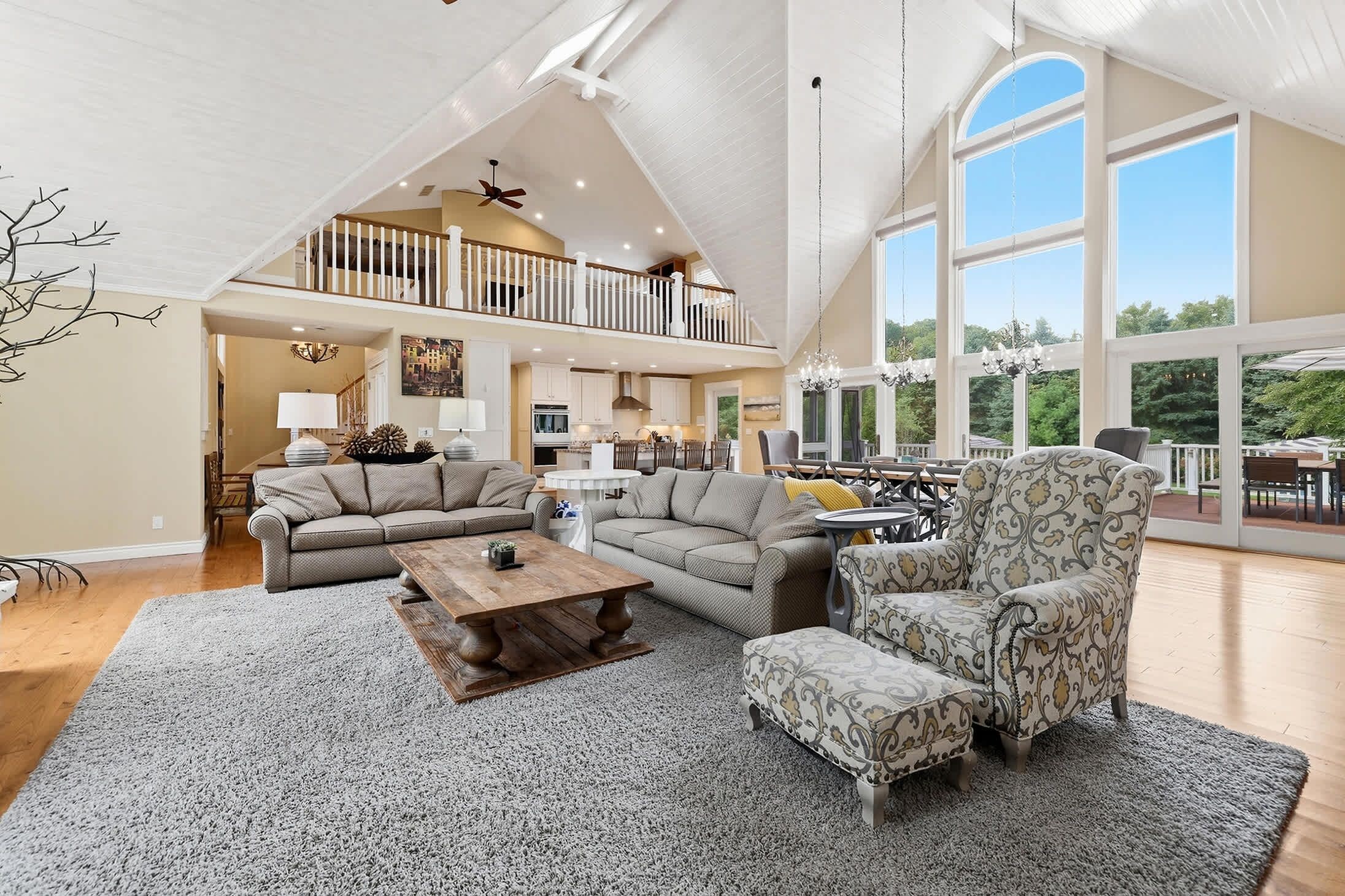 A spacious living area with a high ceiling, a dining area, and a view of the outdoors.