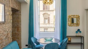A room with a stone wall, a round table with chairs, a window with curtains, and a chandelier. - Solferino apartment near Roma Termini central station (Rome)
