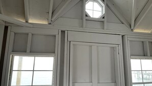 A room with a large window, a smaller skylight, and a view of the water outside.
