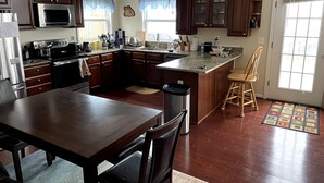 A kitchen with wooden cabinets, a stainless steel refrigerator, a microwave, and a large island with a sink.