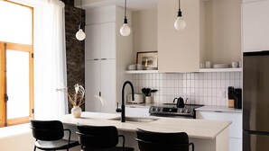 A modern kitchen with a central island, black chairs, a sink, a stove, and hanging pendant lights. -  Maison Place Royale by Luxury In Transit (Montreal)
