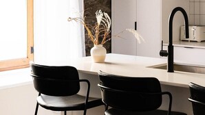 A modern kitchen with a central island, black bar stools, a vase with dried plants, and pendant lights. -  Maison Place Royale by Luxury In Transit (Montreal)