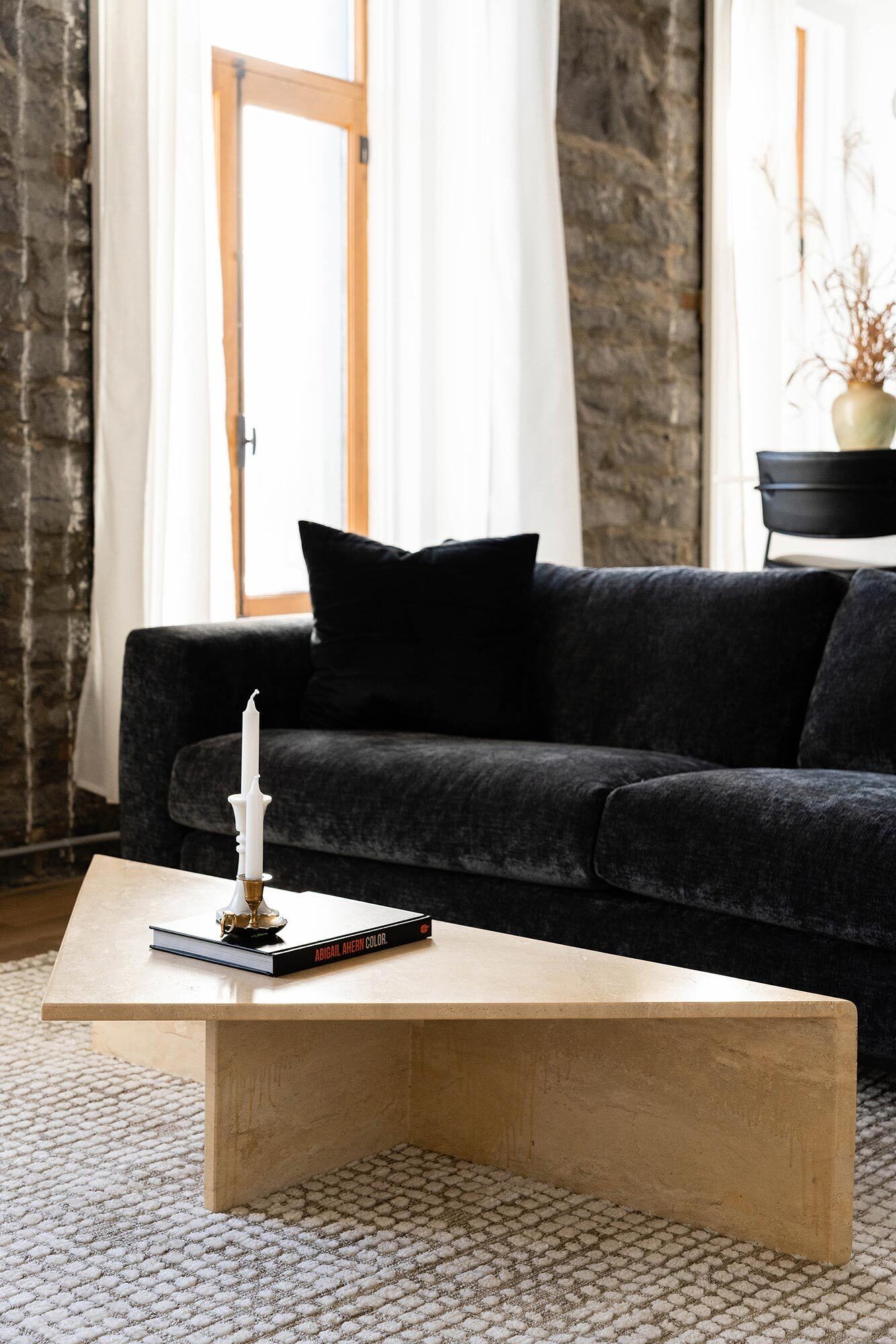Een woonkamer met een donkergrijze bank, een houten salontafel en een boek getiteld 