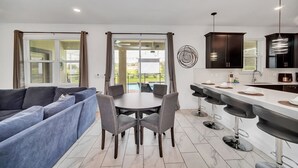 Een moderne keuken met een eethoek, een groot raam met gordijnen en uitzicht op de omgeving.