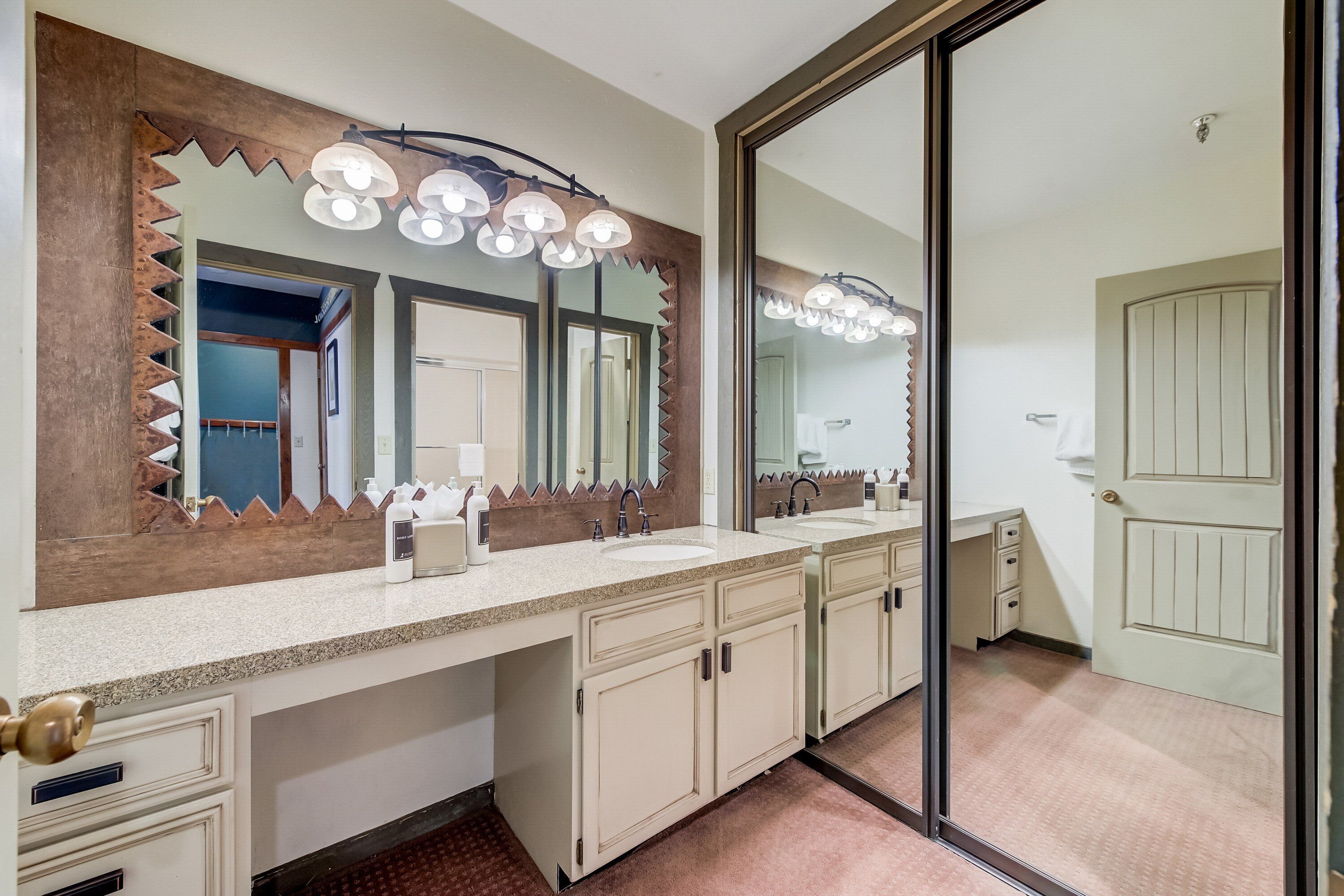 A bathroom with two sinks, a large mirror, and a vanity with drawers.
