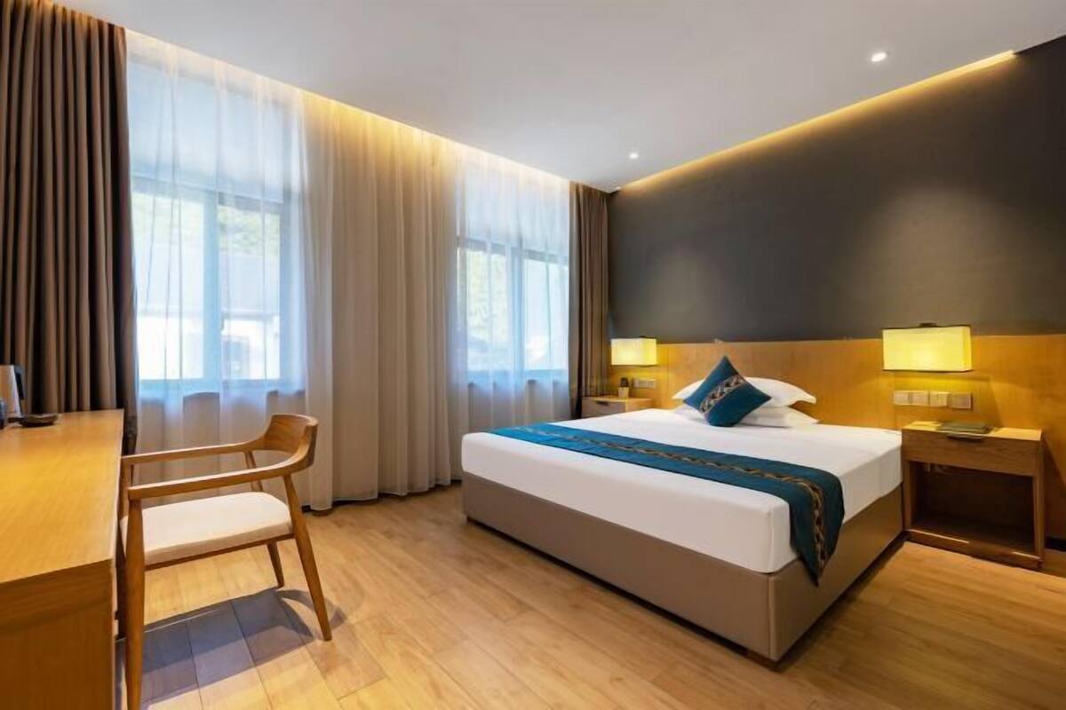 A hotel room with a bed, bedside tables, a desk, and a chair.
