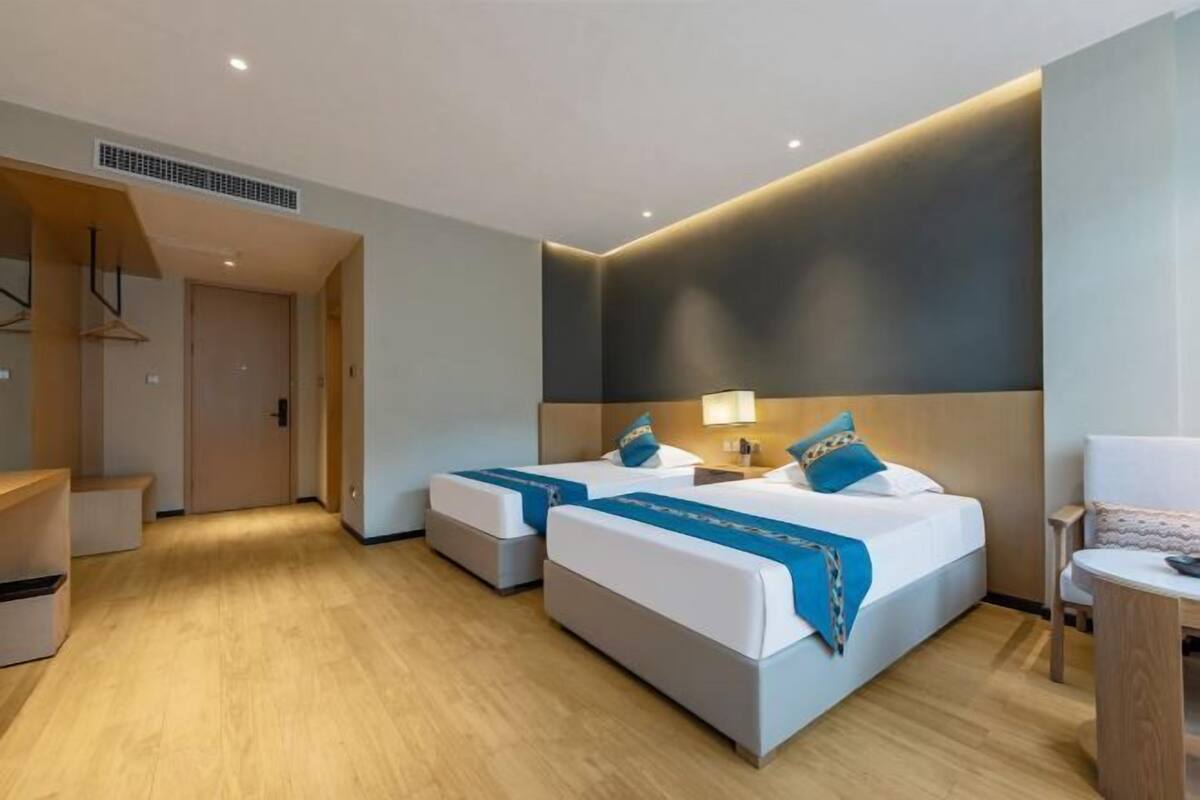 A hotel room with two beds, a desk, and a chair.