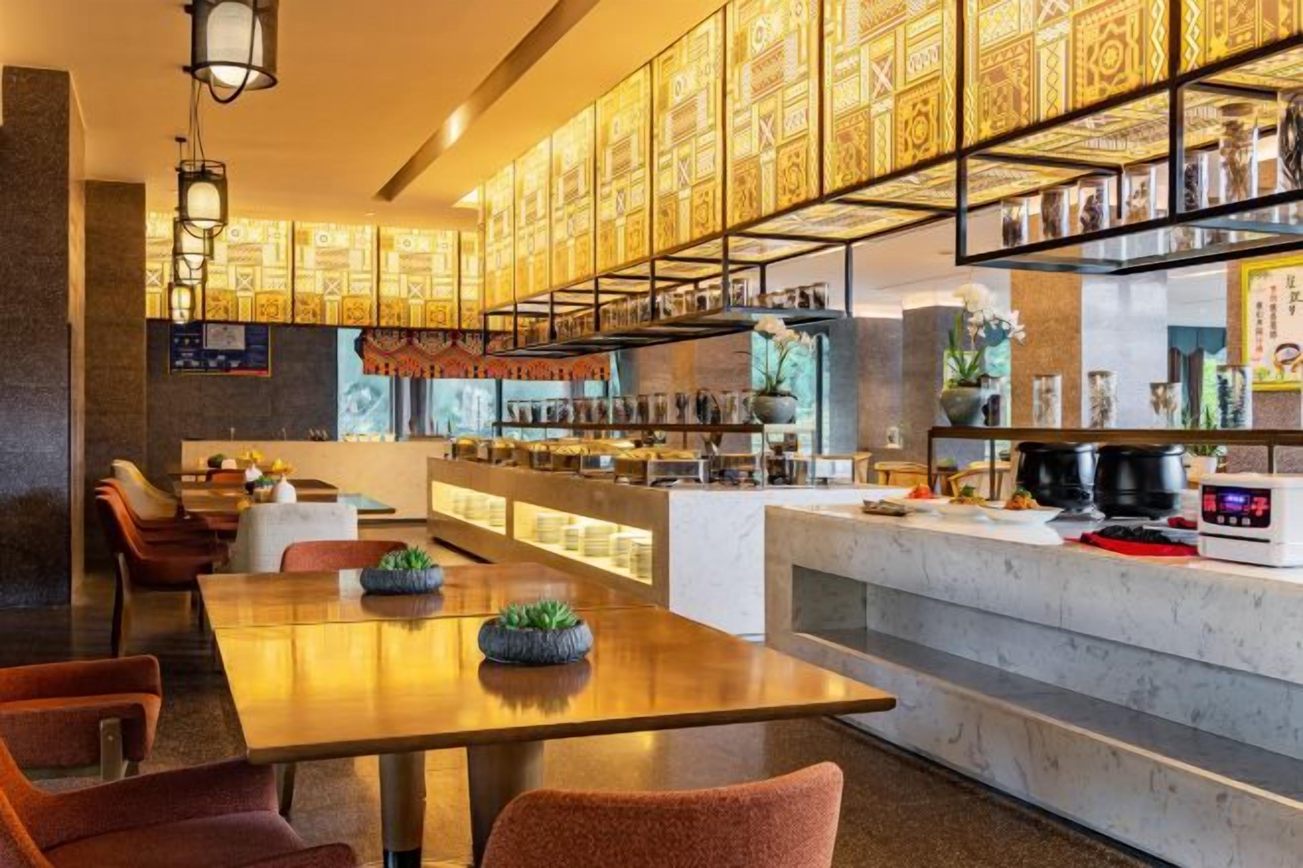 Un restaurante con una barra alargada, varias zonas de estar y un techo decorativo.