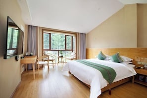Una habitación de hotel con cama, escritorio, silla, televisor y ventana.