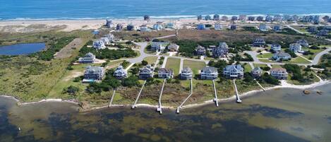An aerial view of a coastal residential area with houses, a beach, and a water body.