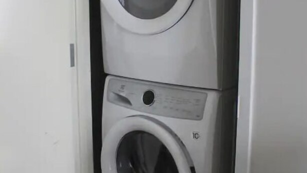A stacked washer and dryer unit in a white cabinet.