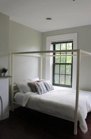 A single bed with a canopy in a room with a large window and a small plant on the nightstand. - Chic, Renovated Brownstone in Prime DT Albany (Albany)