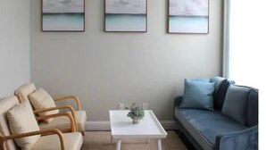 A living room with a sofa, two armchairs, a coffee table, and three wall-mounted paintings. - Chic, Renovated Brownstone in Prime DT Albany (Albany)