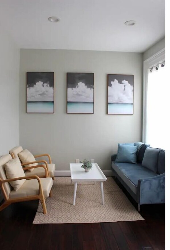 A living room with a sofa, two armchairs, a coffee table, and three wall-mounted paintings. - Chic, Renovated Brownstone in Prime DT Albany (Albany)