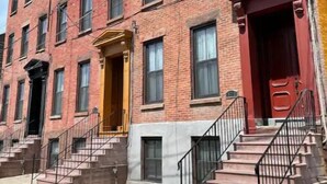 A row of brick townhouses with multiple windows and a red door. - Chic, Renovated Brownstone in Prime DT Albany (Albany)